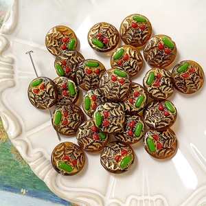 Detailed view of amber glass beads with gold spider web relief and colorful DIY accents