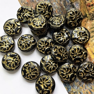 Macro view of vintage black round beads with detailed gold peony floral relief carvings