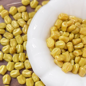 Macro detail of yellow tulip-shaped beads with pearlescent finish for DIY jewelry