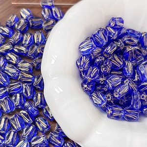Macro detail of cobalt blue glass tulip beads with gold accents in a ceramic bowl