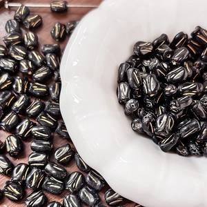 Close-up of black glass tulip beads with gold details on a decorative white dish