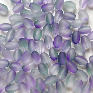 Macro shot of frosted olive-shaped gradient beads in purple and green for DIY jewelry