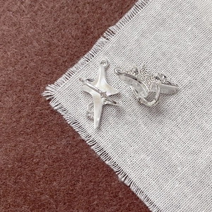 Primo piano di orecchini a stella in argento con pietre luminose su sfondo in tessuto