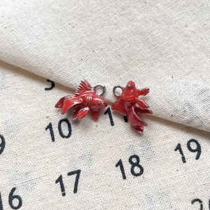 Vue détaillée de deux breloques poissons en émail rouge pour bijoux DIY et bracelets
