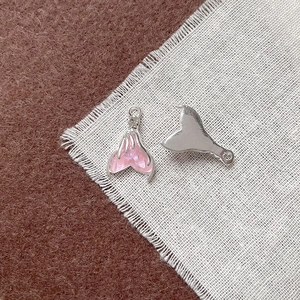 Dettaglio macro di ciondoli a coda di sirena con smalto rosa e strass per gioielli fai-da-te