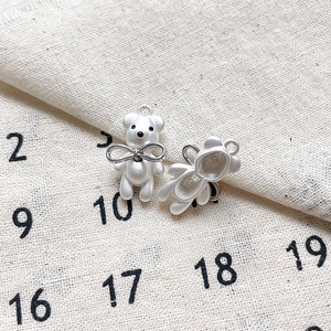 Détail de breloques ours nacrées avec nœuds papillon argentés pour bijoux DIY
