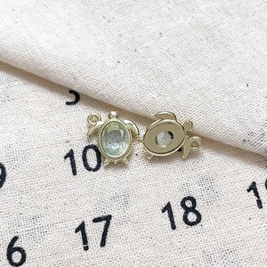 Vue macro des deux côtés d'un pendentif tortue doré avec une pierre précieuse verte