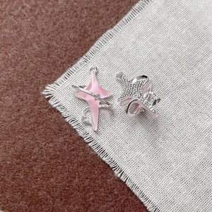 Dettaglio di ciondoli a forma di stella e quadrifoglio rosa e argento per gioielli