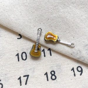 Détail de deux breloques guitares en émail ambré et argent pour création de bijoux DIY