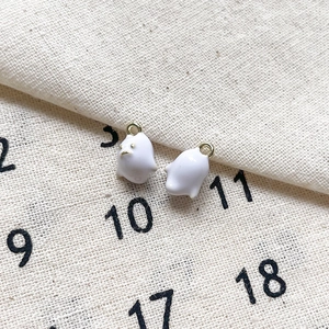Vue macro de mignons pendentifs fantômes en émail blanc avec crochets dorés sur tissu
