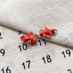 Gros plan de breloques poissons rouges en émail pour la création de bijoux DIY