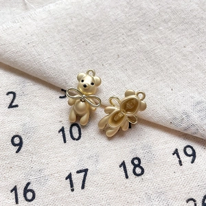 Vue détaillée de pendentifs ours en or mat avec nœud pour la création de bijoux DIY