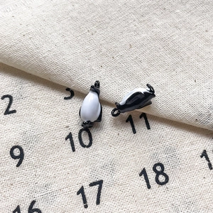 Détail de breloques pingouin en émail pour DIY avec finition goutte d'huile noire et blanche