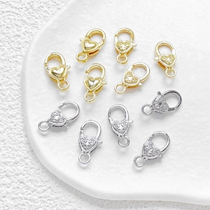 Chiusure a moschettone a cuore in oro e argento per gioielli su un vassoio bianco