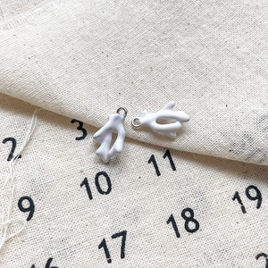 Gros plan de breloques en corail blanc avec boucles argentées pour bijoux DIY