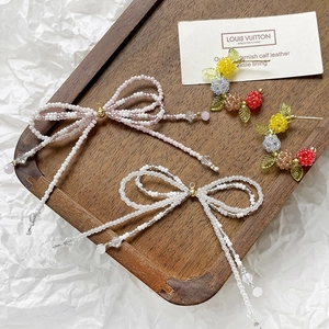 Macro view of beaded bow pendants and berry earrings in a vintage wooden tray