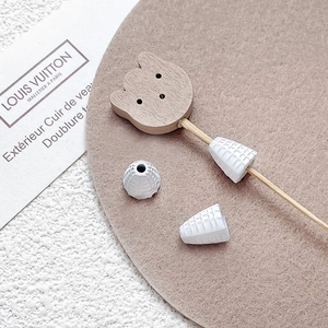 Macro shot of DIY jewelry accessories featuring a wooden bear head and textured cones