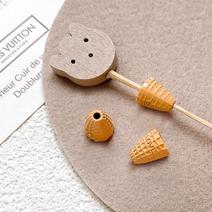 Detail of handcrafted bear charm and orange ice cream beads for DIY jewelry making