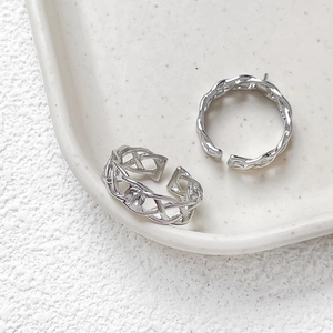 Detail of silver woven texture adjustable open rings on a white ceramic tray