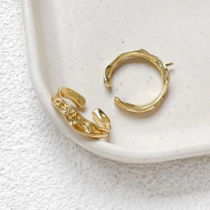 Close-up of irregular 14k gold-plated lava texture stud earrings on white ceramic