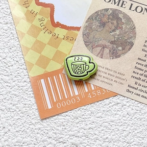 Close-up of green cartoon teacup charm for DIY jewelry making and handmade crafts