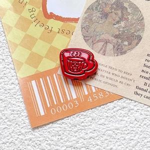 Macro shot of red enamel coffee cup charm with star pattern and detailed relief