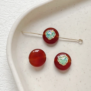 Macro shot of red agate beads with green heart pattern and gold enamel for DIY jewelry