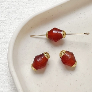 Macro view of olive-shaped red agate beads with gold filigree caps for DIY jewelry making