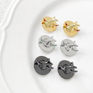 Shark shaped gold silver and black metal pins in a white ceramic dish accessory