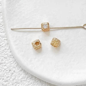 Detailed macro view of 18k gold-plated hammered square beads with zircon for jewelry DIY