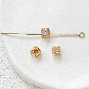 Macro shot of 18k gold-plated cube spacer beads with zircon inlays for DIY jewelry making