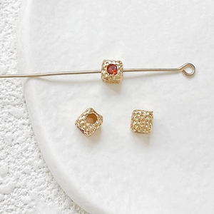 Macro detail of 18k gold plated square beads with red zircon inlay for DIY jewelry