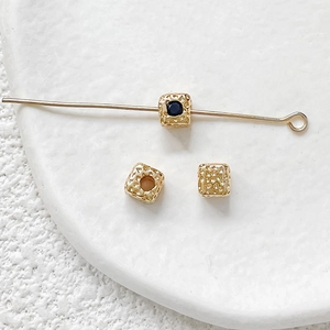 Detailed view of hammered 18k gold-plated square beads with blue zircon for DIY jewelry