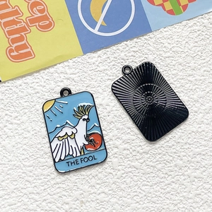 Detailed macro view of The Fool tarot bird charm with colorful enamel and metal sunburst