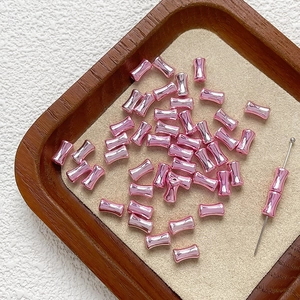 Dettaglio di perle metalliche rosa a forma di bambù per gioielli fai-da-te e bracciali
