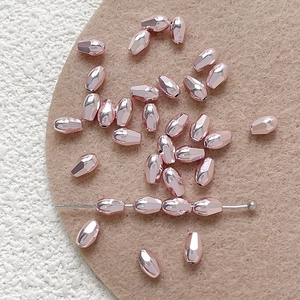 Close-up of rose gold faceted teardrop beads with holes for DIY jewelry making
