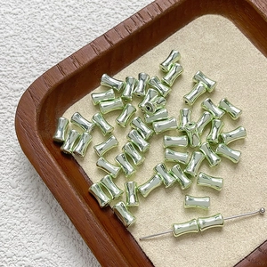 Dettaglio di perline metalliche verde menta a forma di bambù per gioielli DIY
