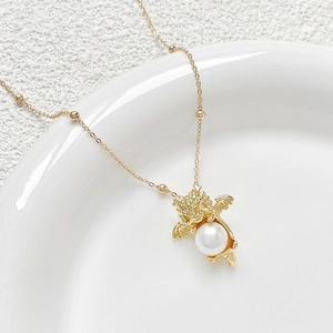 Gold plated dragon pendant necklace with white pearl bead on white ceramic tray