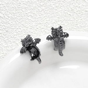 Macro detail of black metal dragon charms with intricate scale textures on white ceramic