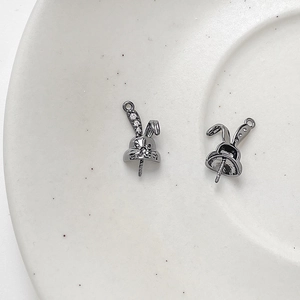 Close-up of rabbit-shaped DIY jewelry pins with zircons on a white ceramic tray