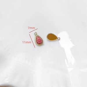 Vue macro de pendentifs goutte en marbre rose avec bordure perlée dorée et tailles