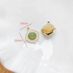 Vue macro d'un pendentif doré vintage de 18mm avec pierre verte et reliefs