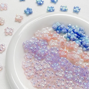 Iridescent flower-shaped beads in pastel pink, lilac, and blue for DIY jewelry crafting