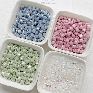 Close-up of pastel colored star-shaped glass beads with dual-hole design for DIY jewelry