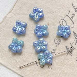 Close-up of iridescent light blue flower beads with horizontal holes for DIY jewelry