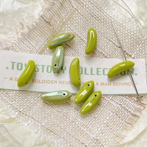 Macro shot of mini glass banana beads in glossy and iridescent green for DIY jewelry