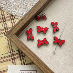 Detailed view of red butterfly charms with dark metal edges for DIY jewelry making