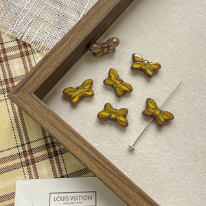 Macro shot of amber glass butterfly beads with dark textures for DIY jewelry making