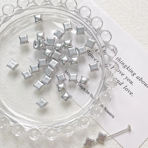 Macro shot of silver matte star beads on a glass tray for DIY jewelry making accessories