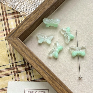 Macro view of translucent light green butterfly glass beads showing the central drill hole